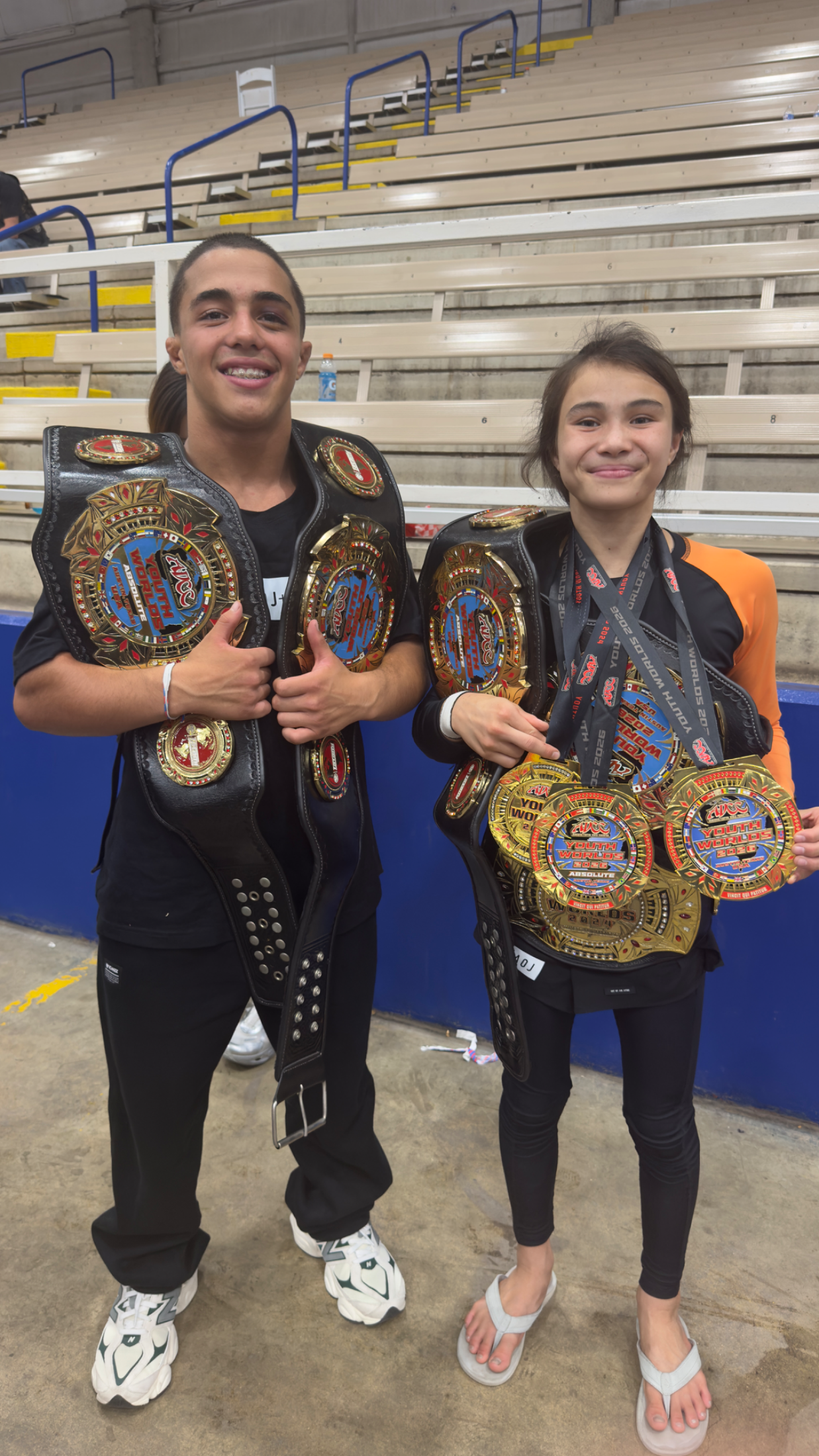 Bailey Heinsohn with Icaro Moreno at 2026 ADCC Youth World Championships in Austin, Texas holding their championship belts and medals