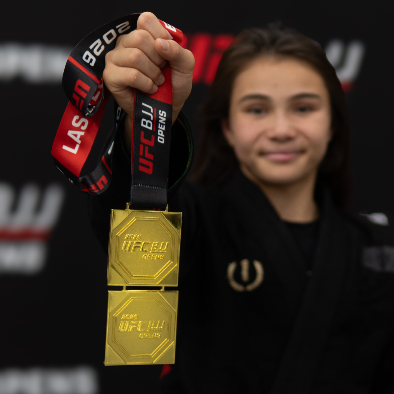 Bailey Heinsohn holding double gold medals she won at 2026 UFC BJJ Open — Las Vegas