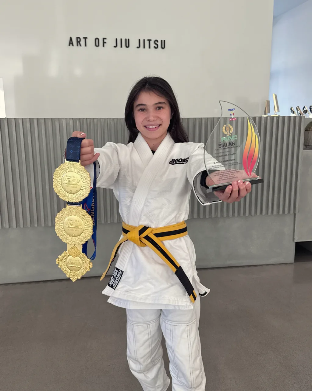 Bailey Heinsohn holding three gold medals and the Siklab Award after the 2025 JJIF World Championships in Thailand.